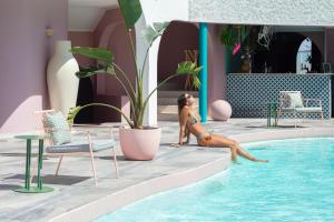 a woman in a bikini is sitting next to a swimming pool at Hotel Rocas de Bahía in Bahia Inglesa