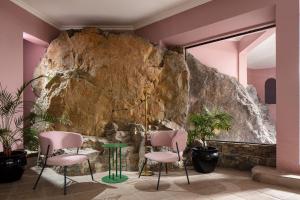Habitación con 2 sillas y pared de piedra. en Hotel Rocas de Bahía, en Bahía Inglesa
