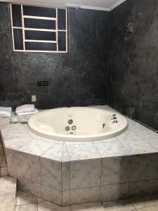 a bath tub in a bathroom with a black wall at Hotel Vip's in Cruz Alta