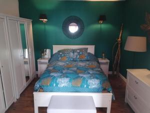 una camera da letto con un letto e una parete verde di La maison à la porte bleue a Voutezac