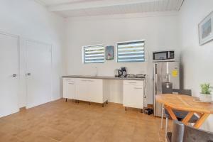 uma cozinha com armários brancos, uma mesa e um frigorífico em Kas Mango in Kralendijk em Kralendijk