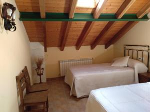 sypialnia z 2 łóżkami i drewnianym sufitem w obiekcie Casa Rural El Pinar w mieście Acebedo