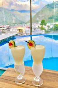 two martini glasses with a bird on top of a table at Destiny Hotel in Baños