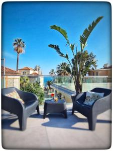 une terrasse avec 2 chaises, une table et un palmier dans l'établissement Le Vallaya Suites & Spa, à Menton