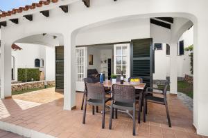 a patio with a wooden table and chairs at Villa Las Marinas - 2 Encantadora Villa con piscina a 5 min de la playa in Arenal d'en Castell