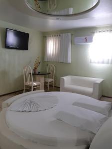 a bedroom with a white bed and a couch and a table at Hotel Pecato in Santa Rosa