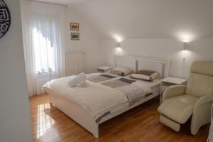 a white bedroom with a bed and a chair at Chalet Lana with Hot Tub in Gozd Martuljek