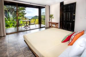 a bedroom with a bed and a large window at Tiki Villas Rainforest Lodge - Adults Only in Uvita