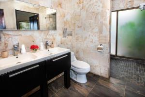 a bathroom with a sink and a toilet and a mirror at Tiki Villas Rainforest Lodge - Adults Only in Uvita +84 photos