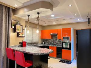 a kitchen with orange cabinets and a counter with red chairs at Villa Haitam Marrakech in Oubadine