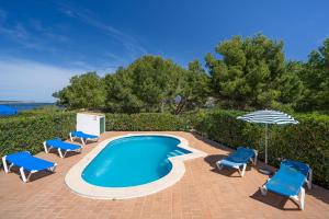 uma piscina com cadeiras e um guarda-sol em Villa LAS MARINAS - 4, con piscina privada y a 5 minutos de la playa em Arenal d'en Castell