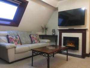 a living room with a couch and a fireplace at Stylish Apartment in Stone-Built Former Rectory in Penrith