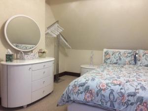Schlafzimmer mit einem Bett, einer Kommode und einem Spiegel in der Unterkunft Stylish Apartment in Stone-Built Former Rectory in Penrith