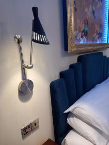 a bed with a blue headboard and a lamp on a wall at The Gatsby Blackpool - Formerly The Windsor in Blackpool