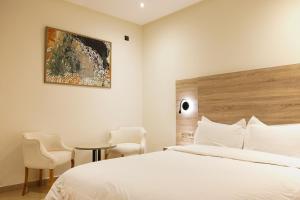 Hotel El Djenina في طنجة: غرفة نوم بسرير ابيض وطاولة وكراسي