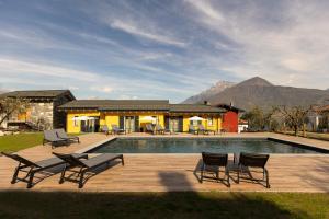 a pool with chairs and a house with mountains in the background at Agriturismo Il Medeghino in Musso