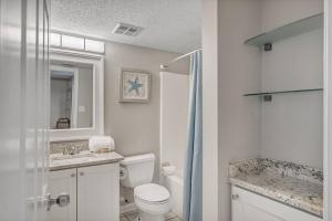 a white bathroom with a toilet and a sink at Fourwinds 803 - Beachfront condo w/ Hall Bunks! - Elevator replacement 4/4-5/24 in Orange Beach +14 photos
