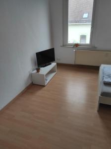 uma sala de estar com televisão num quarto branco em Beautiful 2 bedroom apartment in a quiet area em Kretzschau