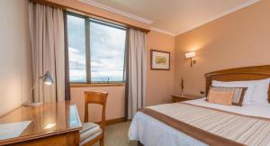 a hotel room with a bed and a desk and a window at Hotel Gran Pacifico in Puerto Montt