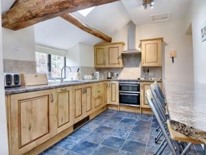 uma cozinha com armários de madeira e pisos em azulejo azul em The Birches em Craswall