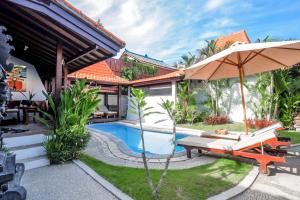 eine Villa mit Swimmingpool und Sonnenschirm in der Unterkunft Surfer Paradise Villas Bali in Canggu