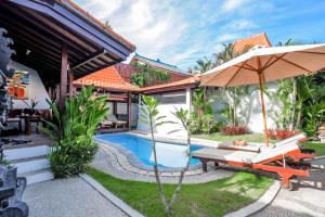 a villa with a swimming pool and an umbrella at Surfer Paradise Villas Bali in Canggu