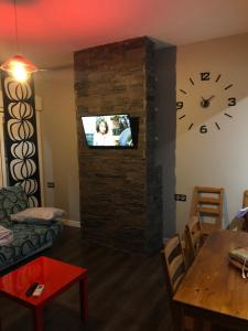 ein Wohnzimmer mit einer Uhr und einem TV an der Wand in der Unterkunft Atico3 - Ciudad de Berja in Berja