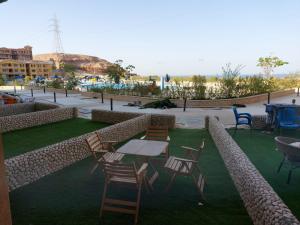 a patio with chairs and tables on the grass at شقه للايجار بورتو السخنه ألعاب مائية فرش مميز فندقي مكيفه in Ain Sokhna