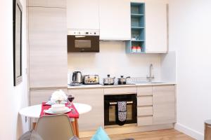 una pequeña cocina con armarios blancos y una mesa en High Spec Luxury Studio Apartment in Sydenham, en Sydenham