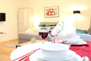 una mesa con dos copas de vino y flores. en High Spec Luxury Studio Apartment in Sydenham, en Sydenham