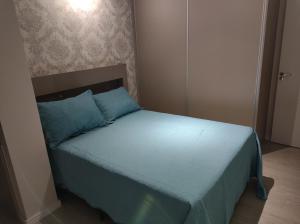 a bed in a bedroom with a blue bedspread and blue pillows at AP novo, bairro nobre, ótima localização, Vale dos Vinhedos, Fenavinho in Bento Gonçalves