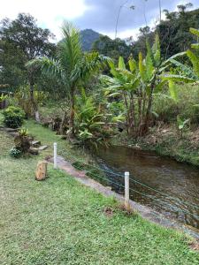 un río con una valla junto a un campo con árboles en Chalet Teresopolis, en Teresópolis