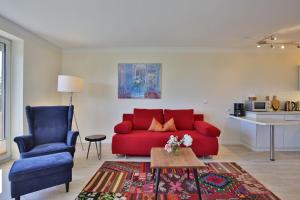een woonkamer met een rode bank en een blauwe stoel bij Strandduene Stranddüne Appartement 3 in Haffkrug