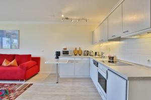 a kitchen with a red couch and a red chair at Strandduene Stranddüne Appartement 3 in Haffkrug