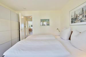 a white bedroom with a large bed with white pillows at Strandduene Stranddüne Appartement 3 in Haffkrug