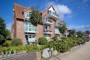 een bakstenen gebouw met balkons en bloemen ervoor bij Strandduene Stranddüne Appartement 3 in Haffkrug