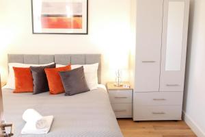 a bedroom with a bed with orange and grey pillows at Exclusive Ensuite Double Room in London +20 photos