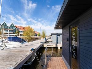 a dock with a boat parked next to a building at Beautiful houseboat in Marina of Volendam with shared pool in Volendam