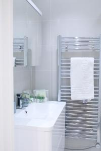 Baño blanco con lavabo y espejo en Executive Bright and Airy Studio Apartment in Sydenham, en Londres