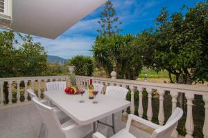 a white table and chairs on a balcony with wine glasses at En Elladi Apartment in Alikanas