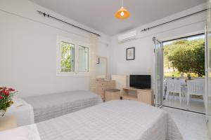 a white bedroom with two beds and a television at En Elladi Apartment in Alikanas