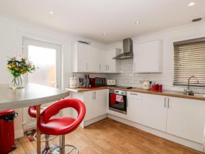 a kitchen with white cabinets and a red chair at The Old Toll Cottage in Muirkirk