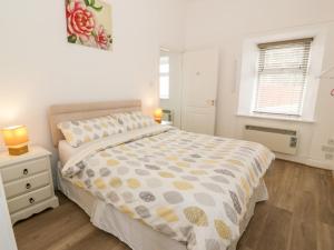 a white bedroom with a bed and a window at The Old Toll Cottage in Muirkirk