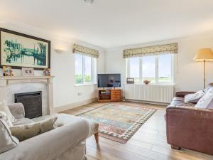 Una sala de estar con un sofá y una chimenea. en Penhallick House, en Tintagel