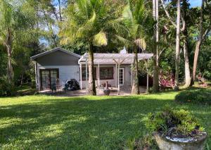 a small white house with palm trees in a yard at Birdsong Bellingen Farm in Thora