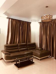 sala de estar con sofá de cuero y cortinas en 3 Rooms Apt @ Crown Imperial Court, en Cameron Highlands