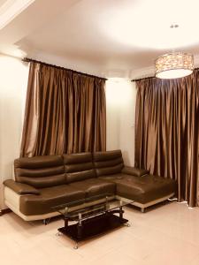 a leather couch in a room with curtains at 3 Rooms Apt @ Crown Imperial Court in Cameron Highlands