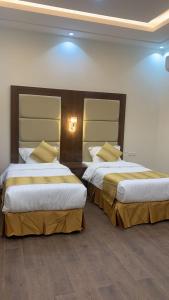 - deux lits dans une chambre d'hôtel avec deux couvre-lits dans l'établissement فندق ايوان, à Qal'at Bishah