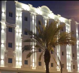un grande edificio bianco con una palma di fronte di فندق ايوان a Qal'at Bishah