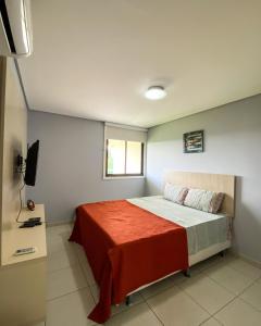 a bedroom with a bed with a red blanket at Flat no Carneiros Beach Resort in Tamandaré